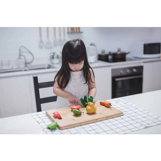 child playing with wonky fruits and vegetables on a kitchen table