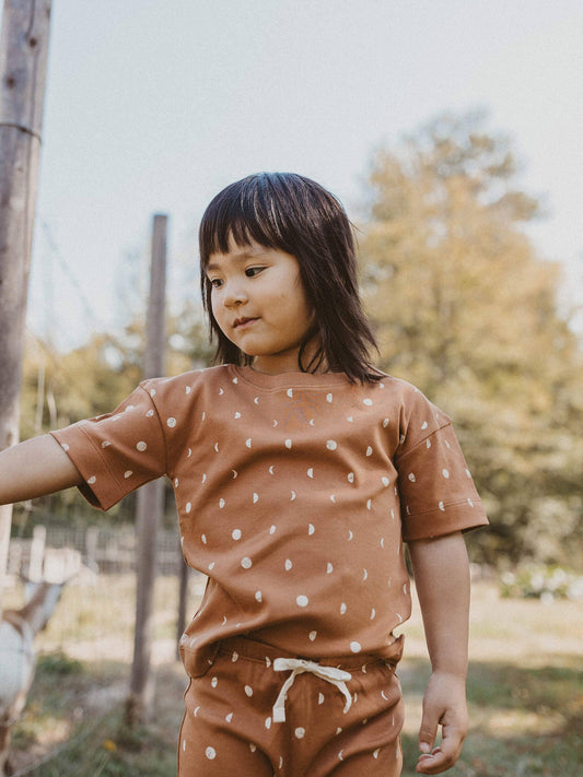 child standing outside wearing terracotta moon organic short sleeve tee