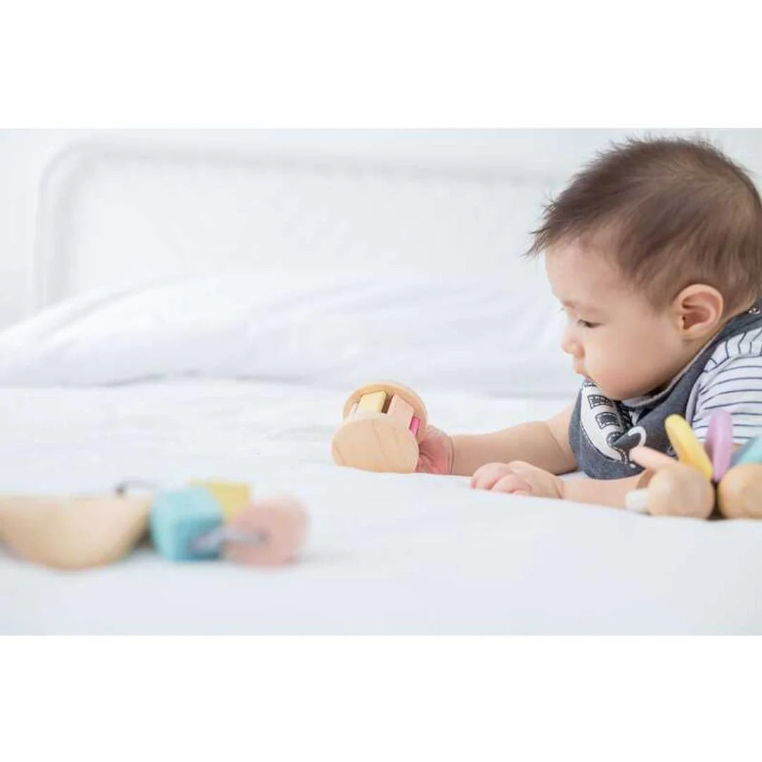 Baby rolling a pastel roller with sound on a bed