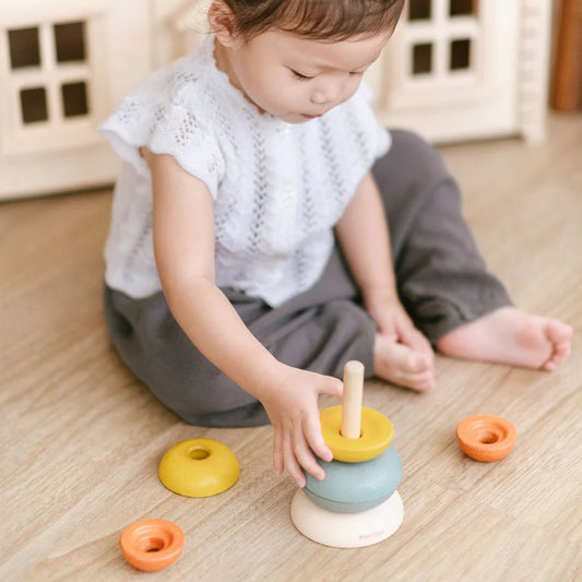 Child sitting on the floor playing with stacking ring cups