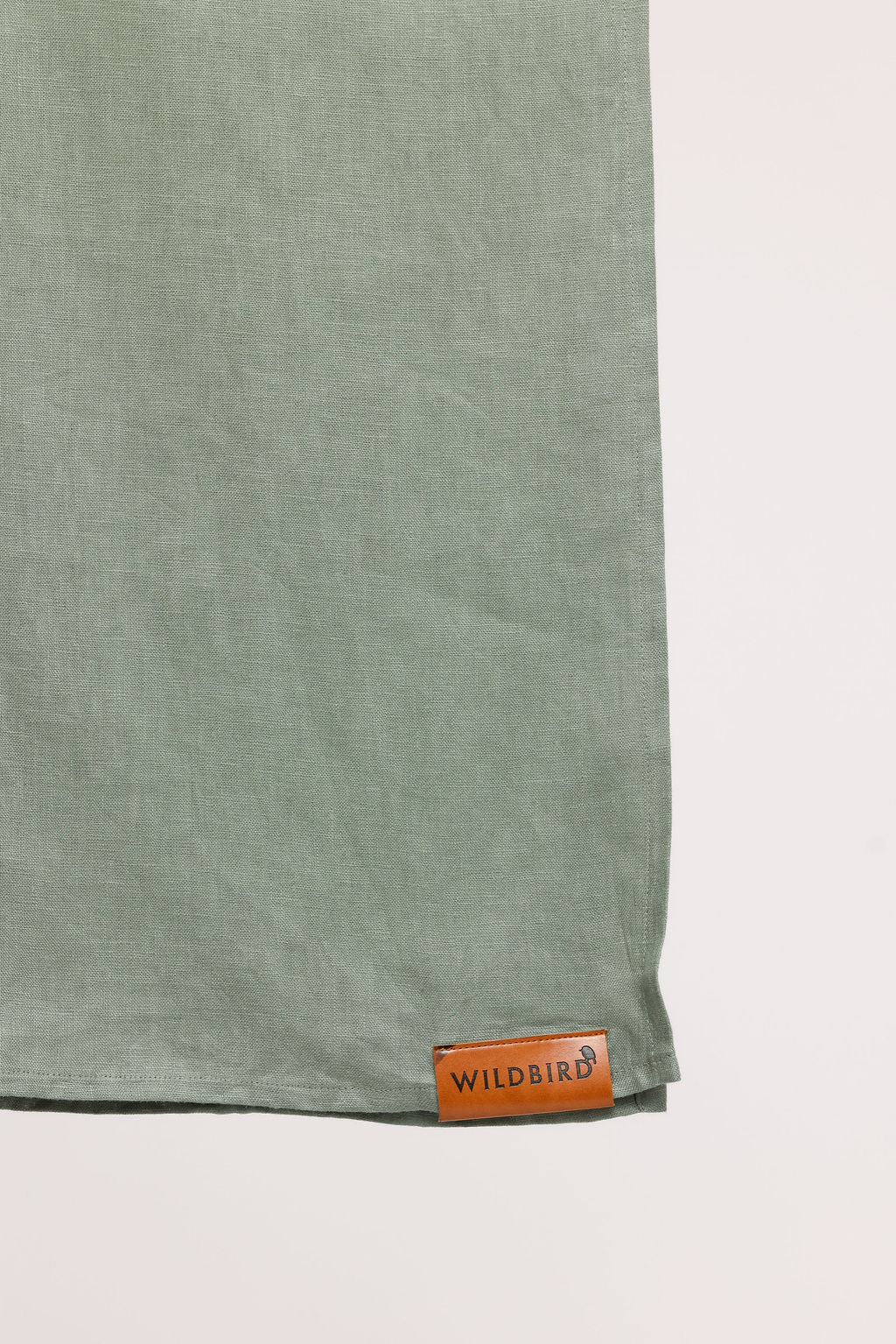 Green fabric with a brown label reading 'Wildbird' on a light gray background