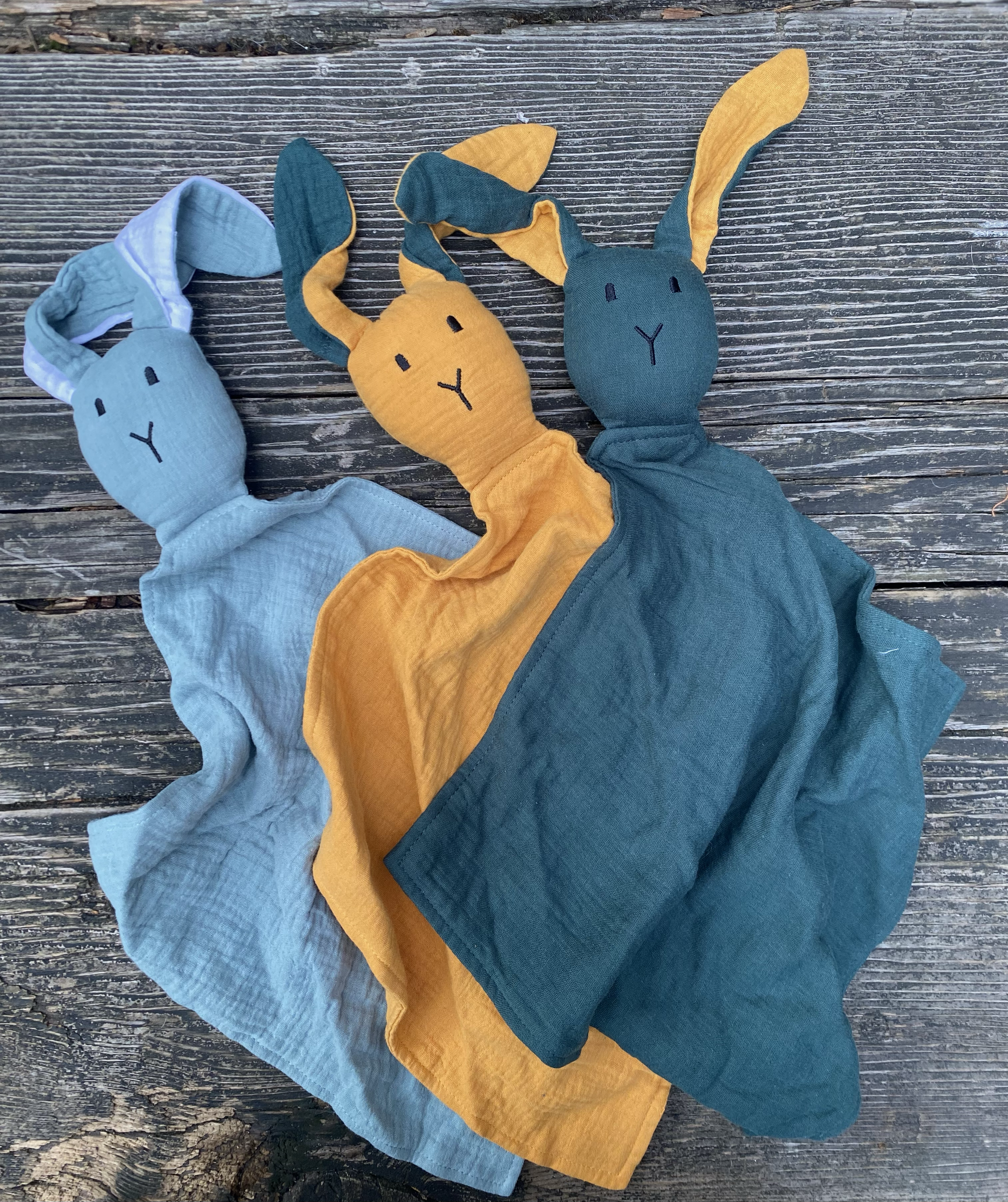 Three soft toy figures of a rabbit, duck, and cat on a wooden surface