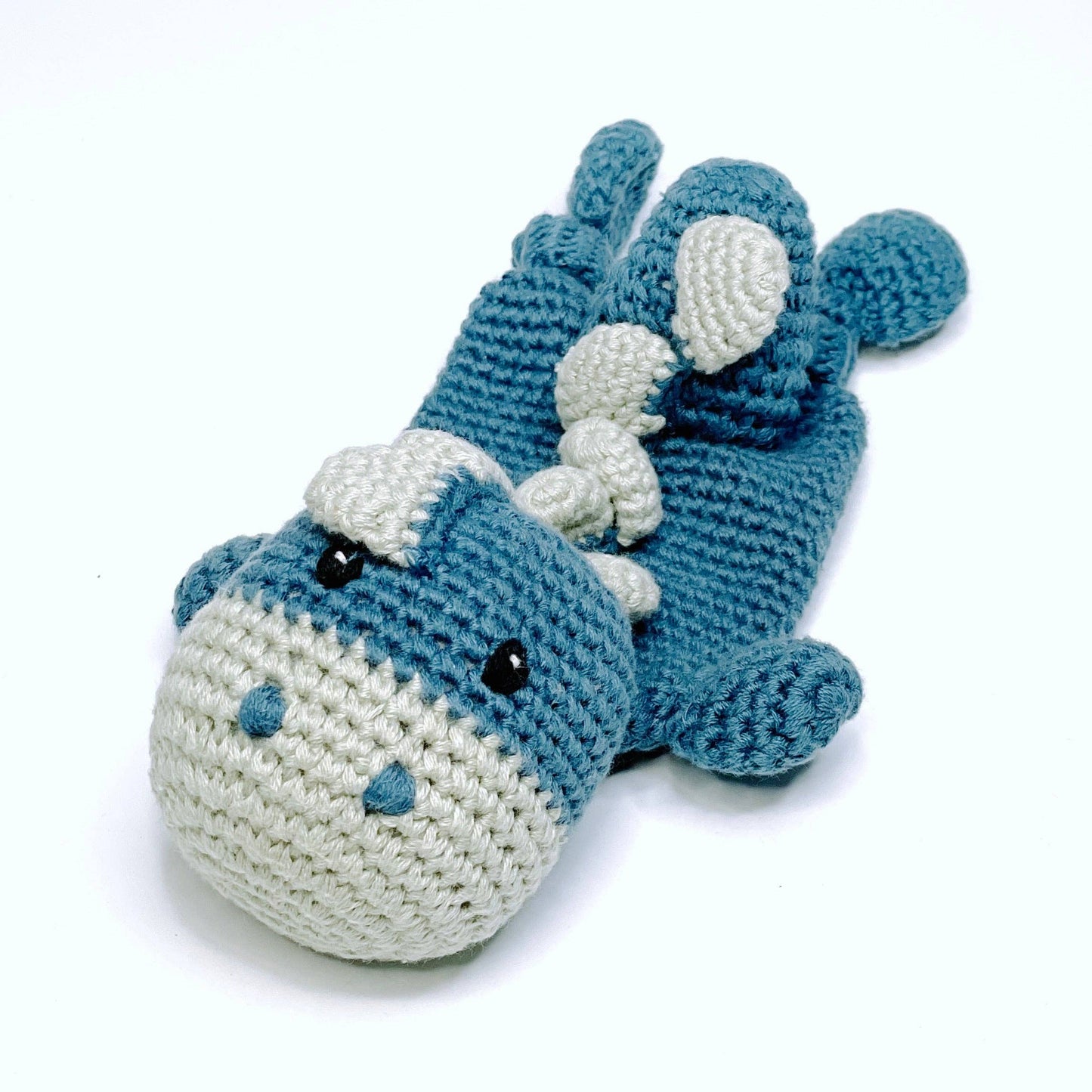 Crocheted blue and white shark toy on a white background