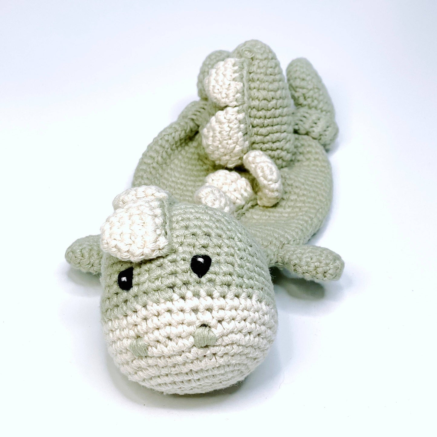 Crocheted toy shark with white fins on a white background