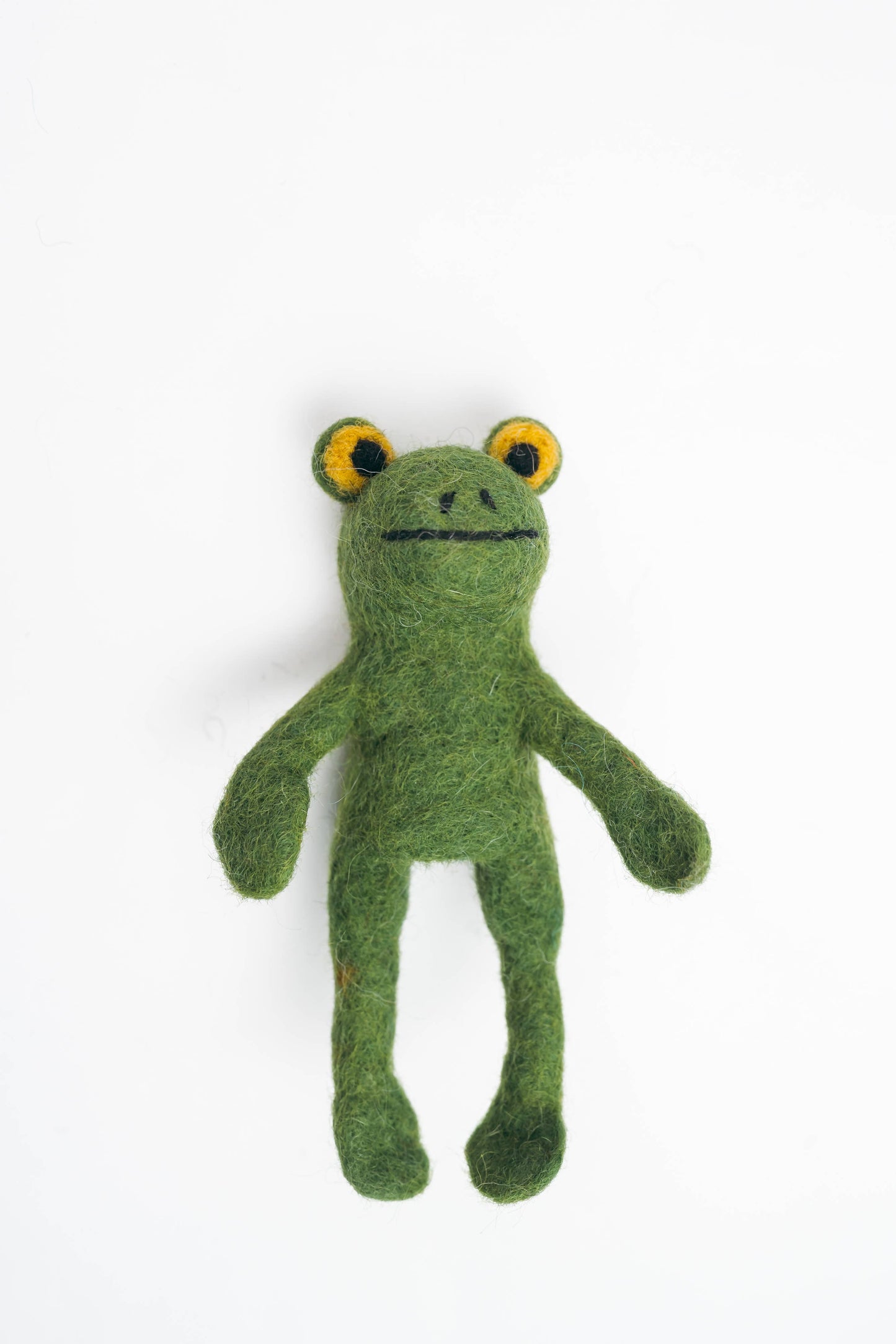 Green felted frog toy on a white background