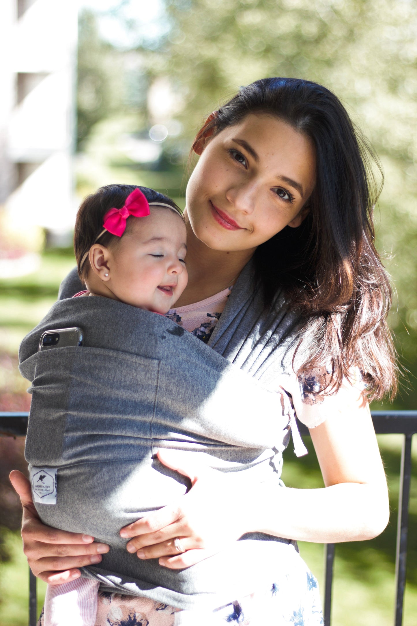 Woman holding a baby in a carrier outdoors