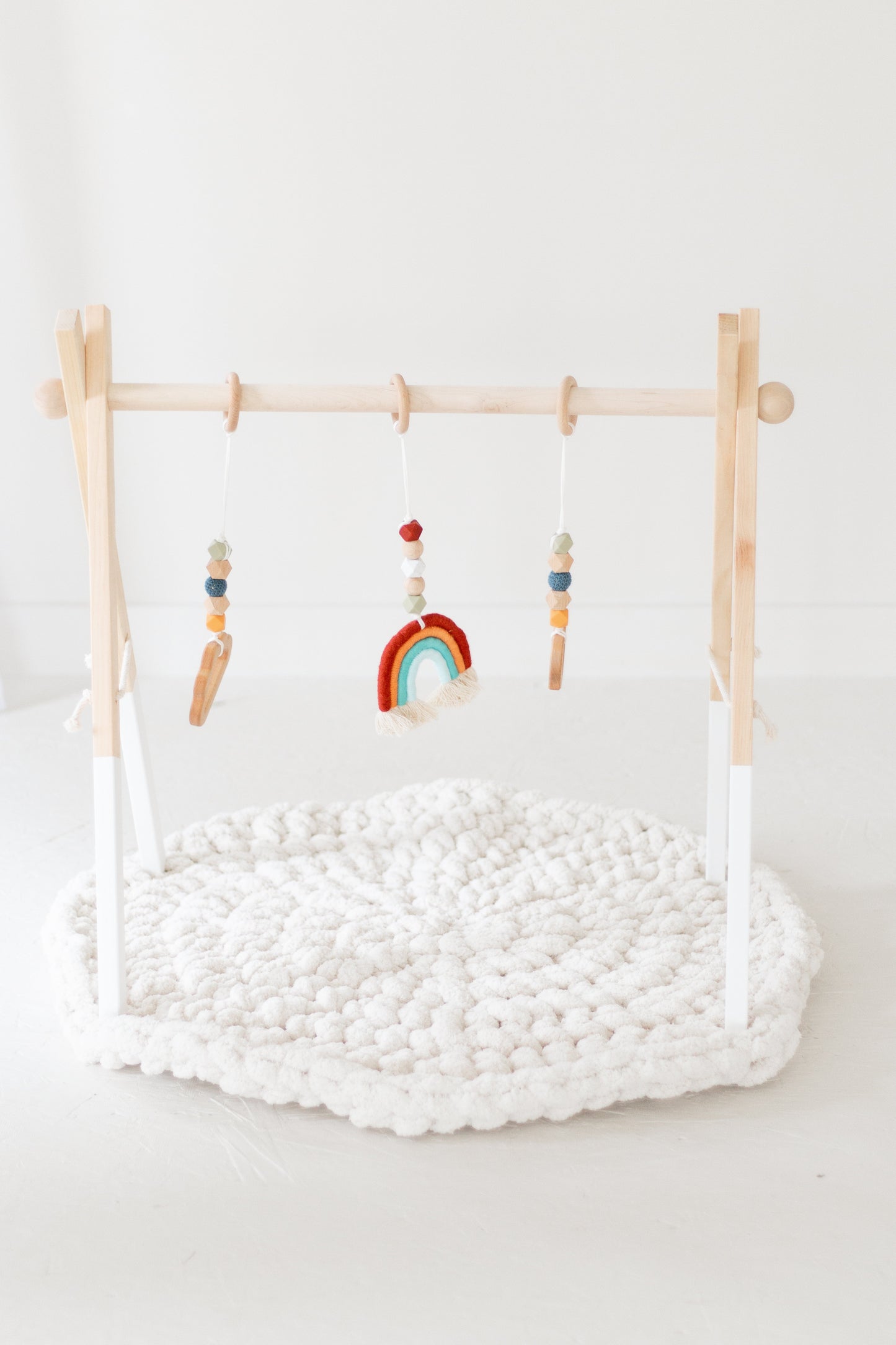 Wooden baby play gym with hanging toys on a white background