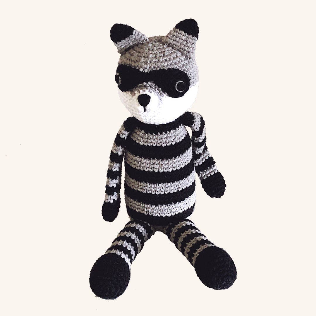 Crocheted raccoon toy with black and white stripes on a white background