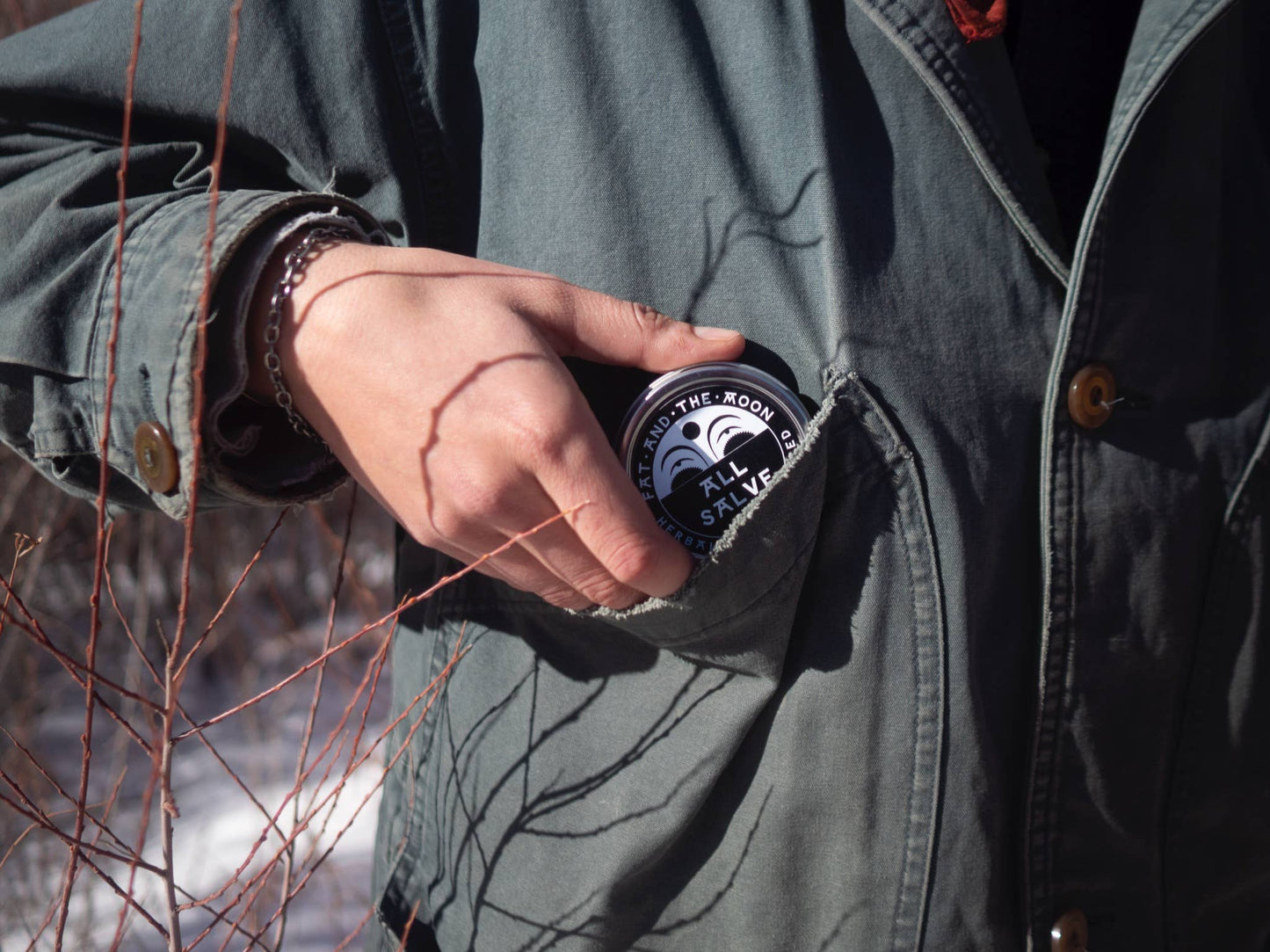 Person wearing a green jacket with a can of 'The Moon' beer in the pocket, standing outdoors.