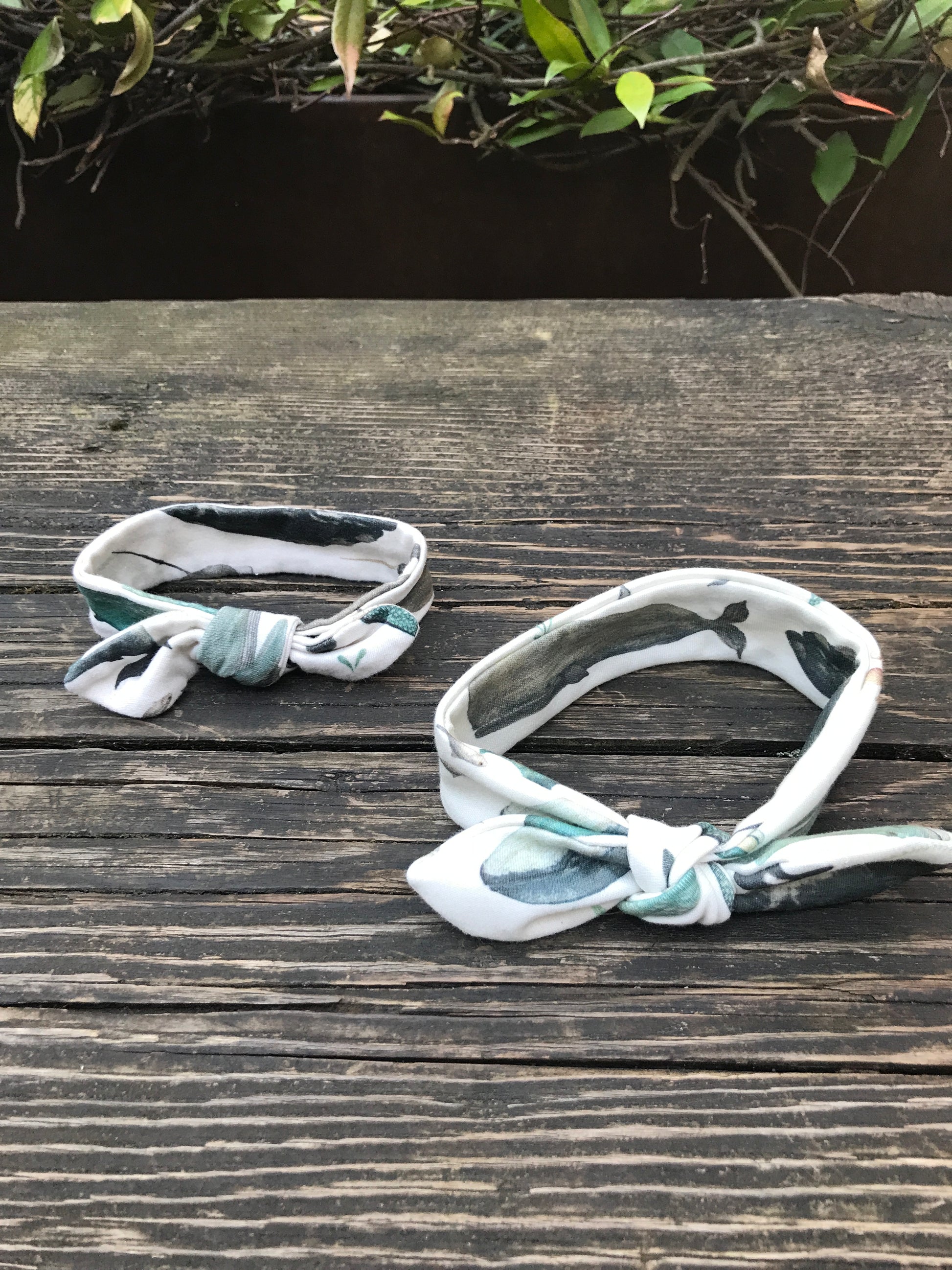 Two Whale Song Baby Head Wraps on a wood bench