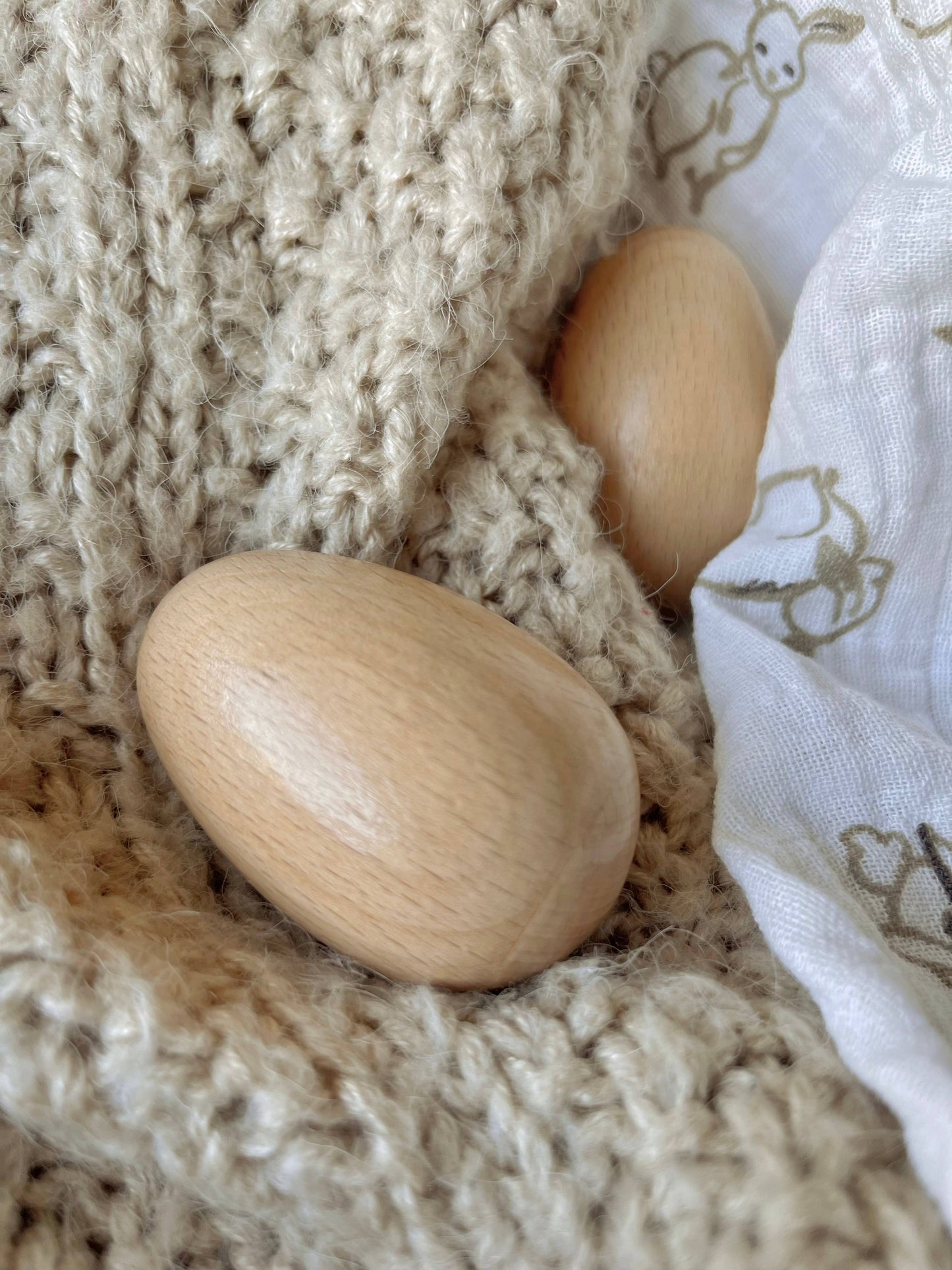 Two wooden egg shakers on a knitted blanket