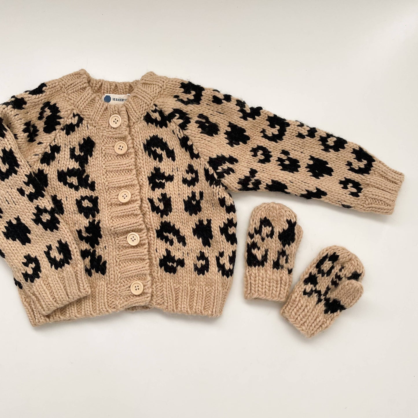 Knitted cardigan with cheetah print and matching mittens on a white background