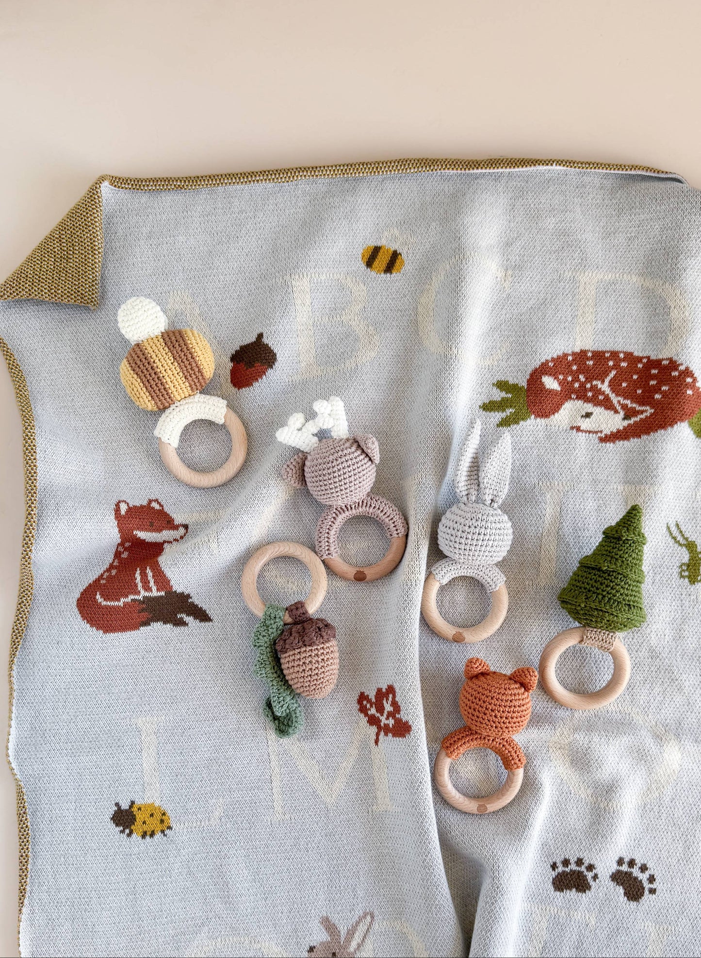 Set of wooden baby teething rings with crochet animal designs on a blanket