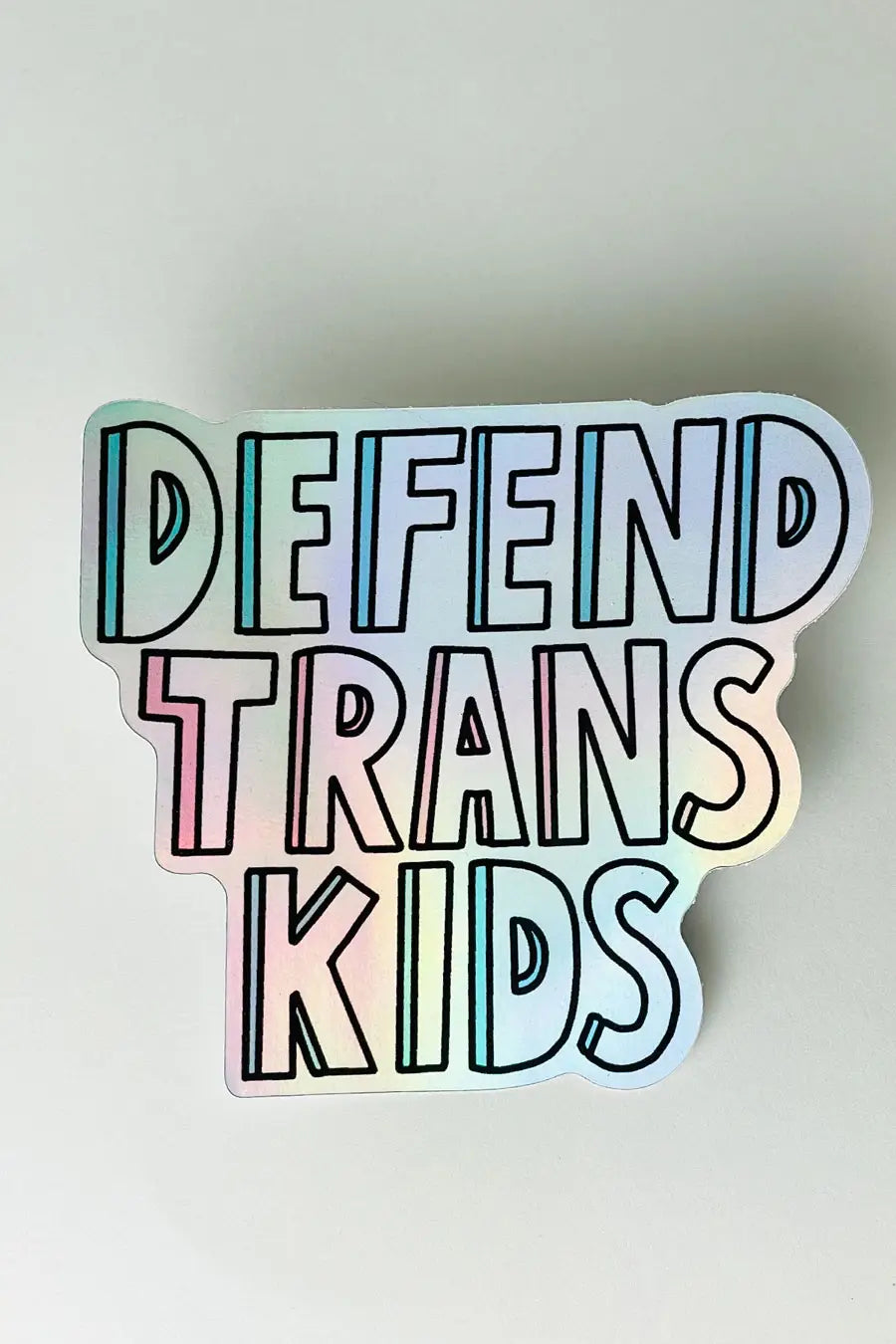 A holographic sticker with the words "Defend Trans Kids"