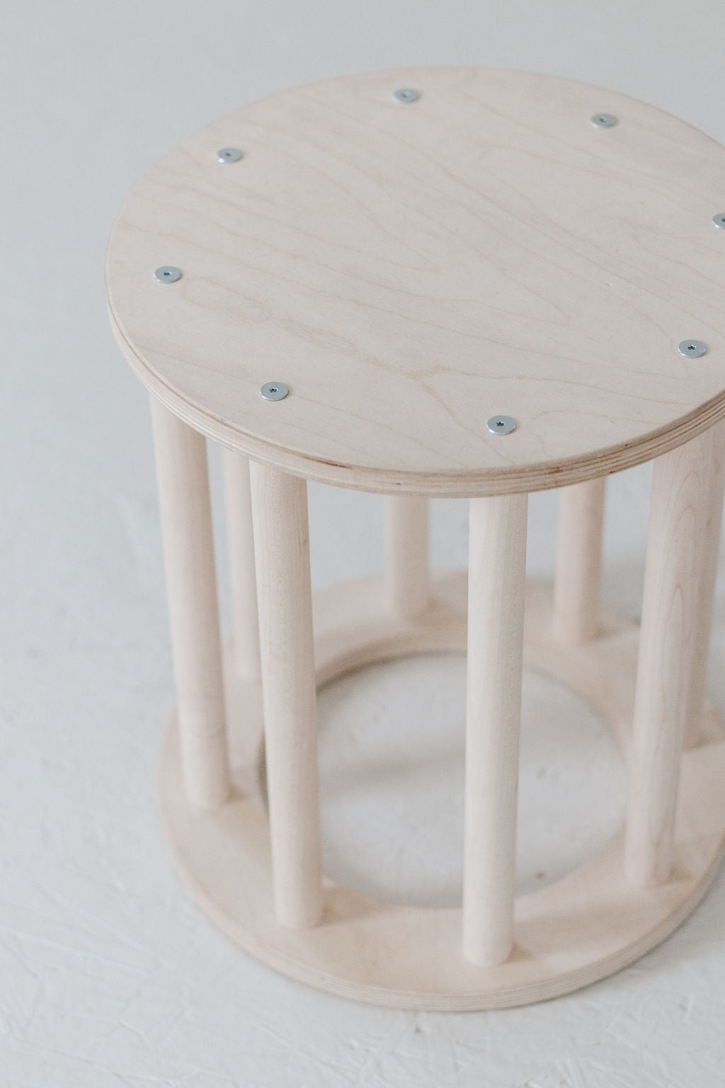Wooden stool with a round seat and cylindrical base on a white background