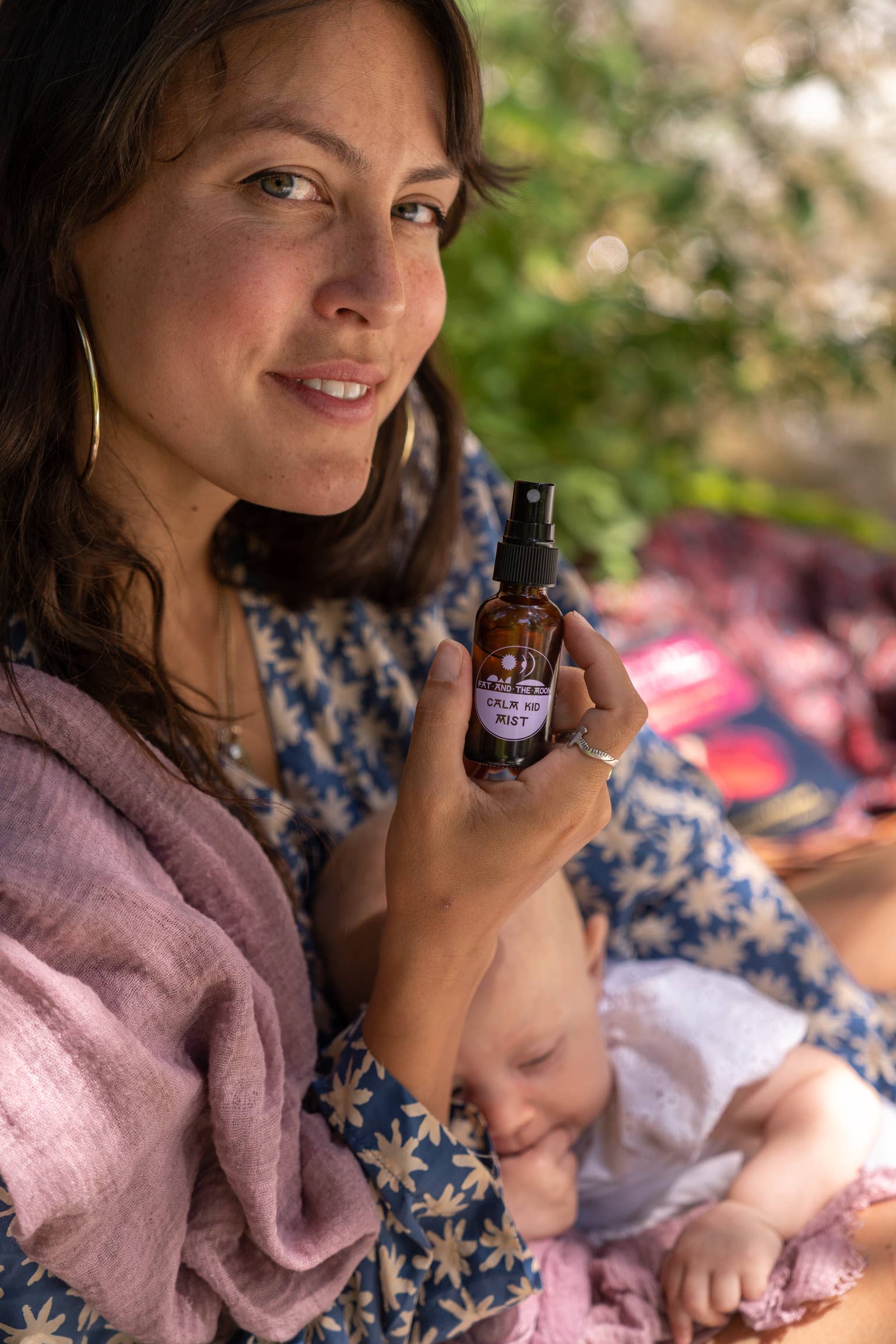 a person holding a baby and a bottle of kid calm mist spray