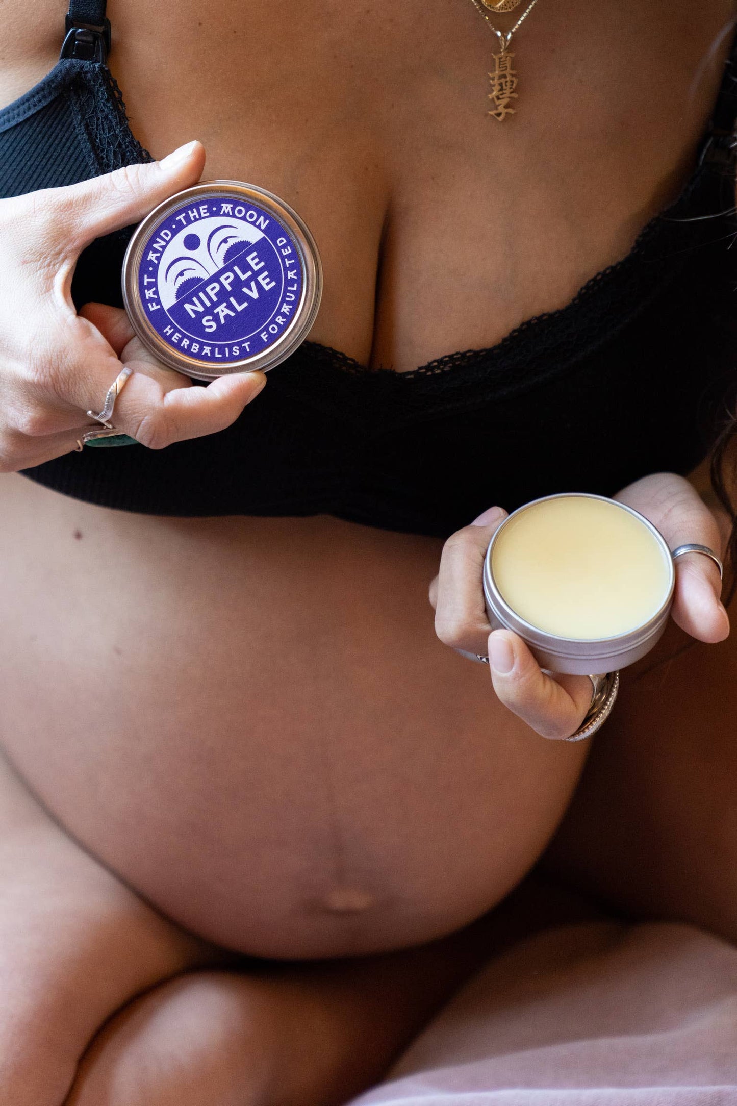 a pregnant person holding a tin of nipple salve
