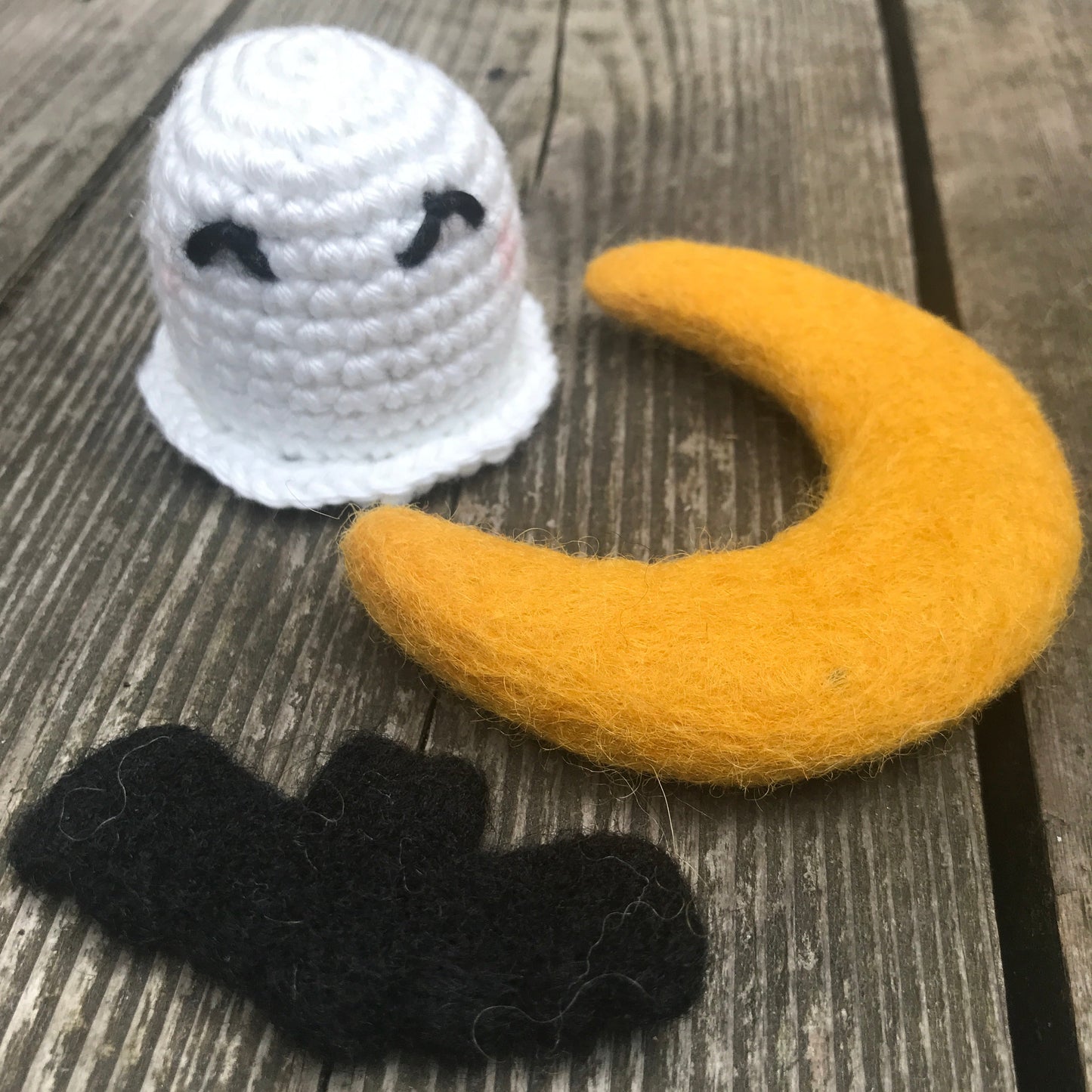 Crocheted moon, star, and ghost on a wooden surface
