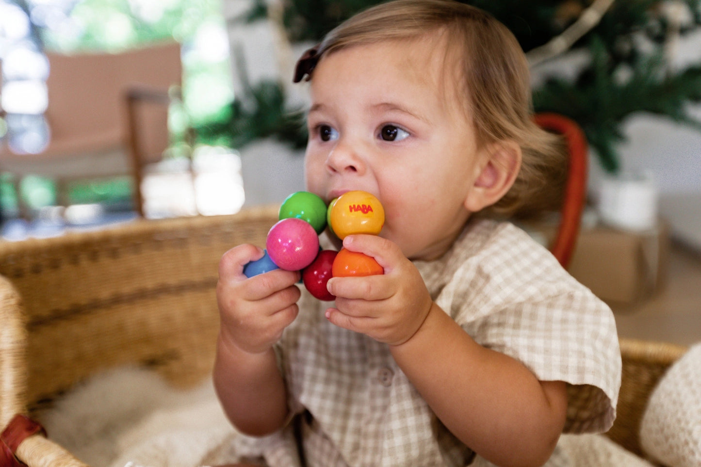 a baby teething on HABA magicka rattle