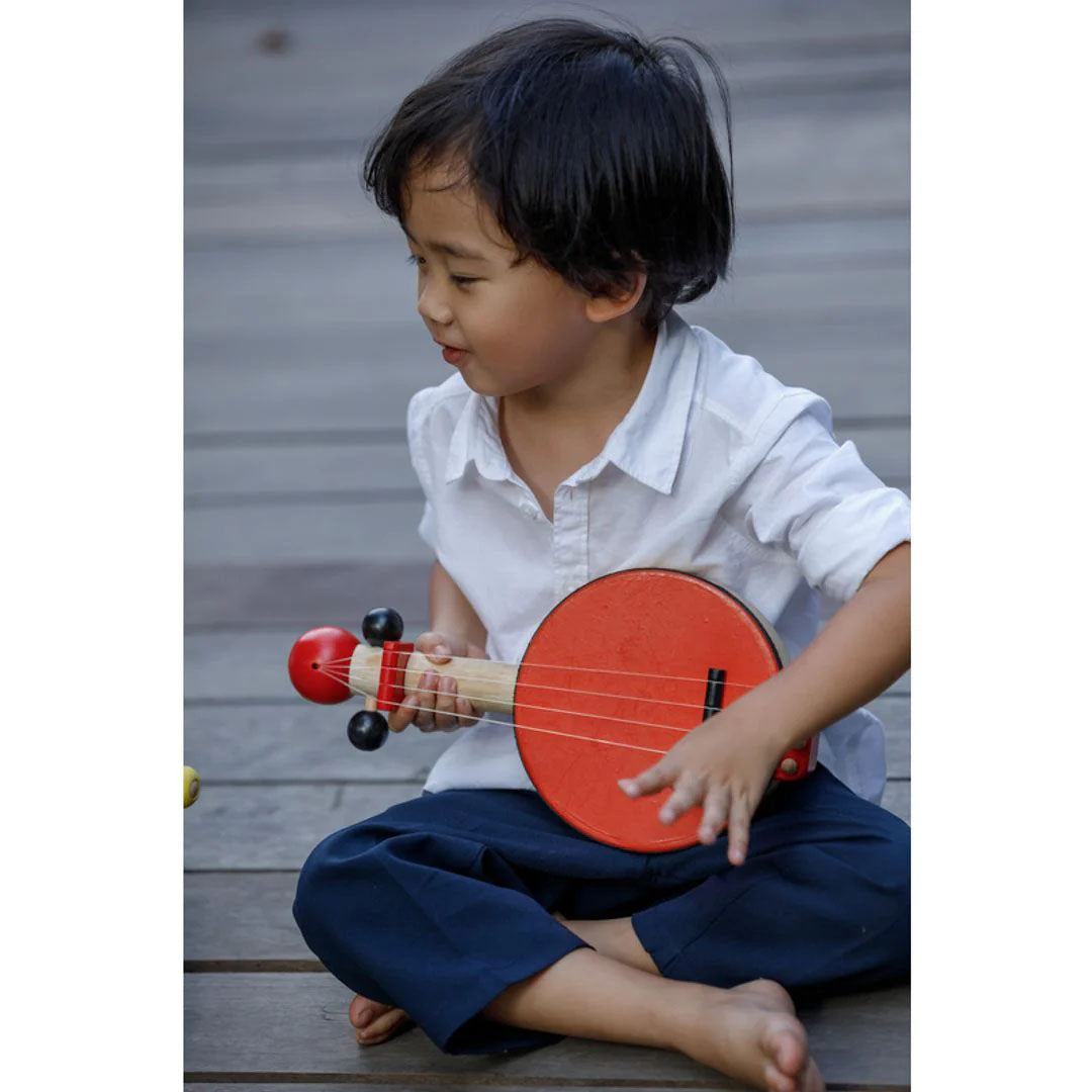 Child sitting Playing a Banjo by Plan Toys