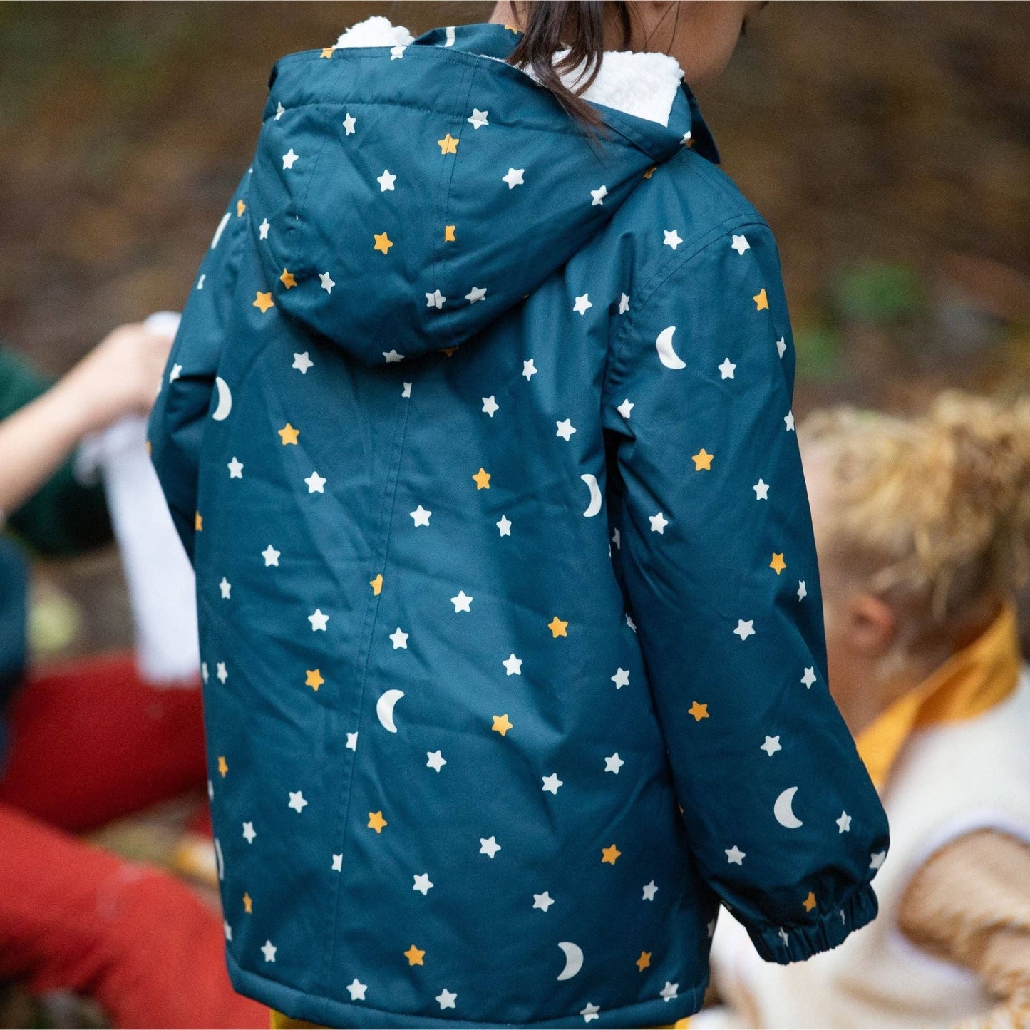 Child standing outside with their back to the camera wearing a starry night recycled winter coat