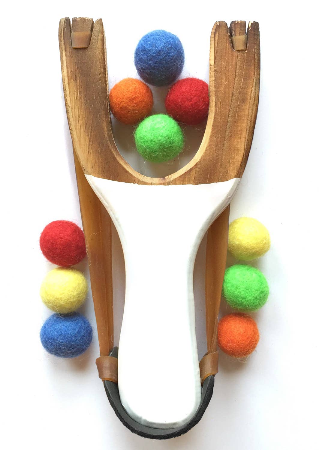 Wooden slingshot with colorful felt balls on a white background