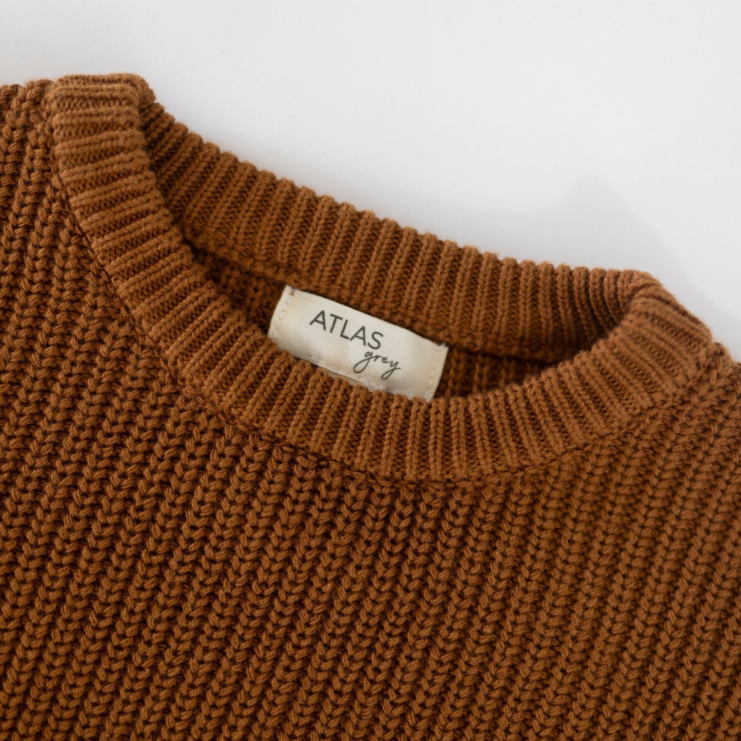 Brown knitted sweater with 'Atlas Grey' label on a white background