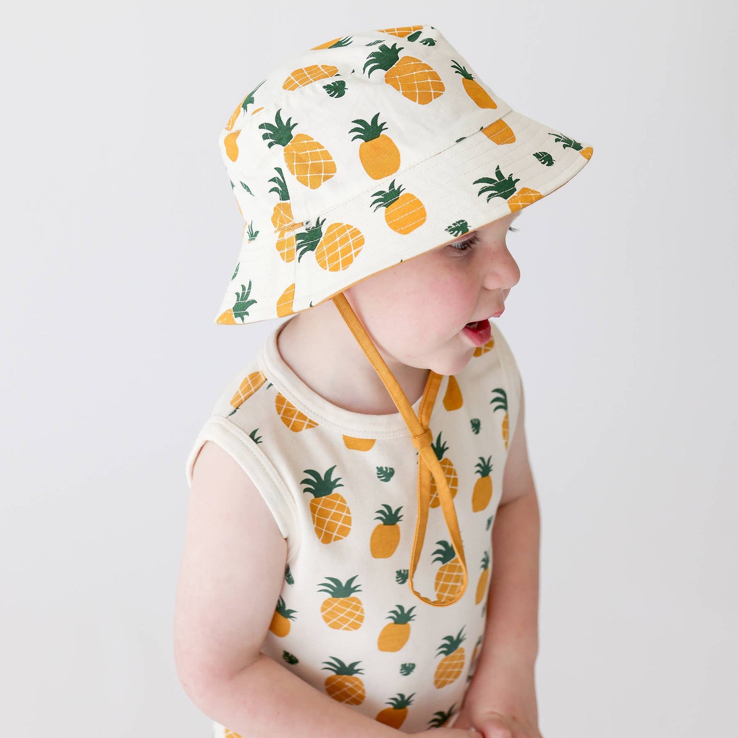 a baby wearing matching pineapple romper and bucket hat