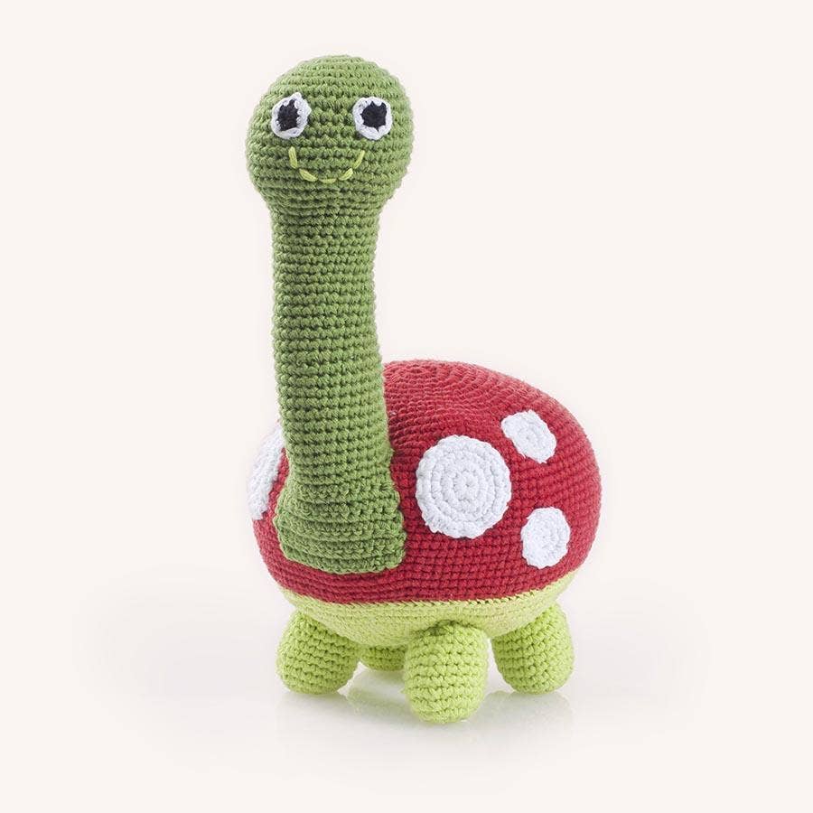 Crocheted turtle toy with a red shell on a white background