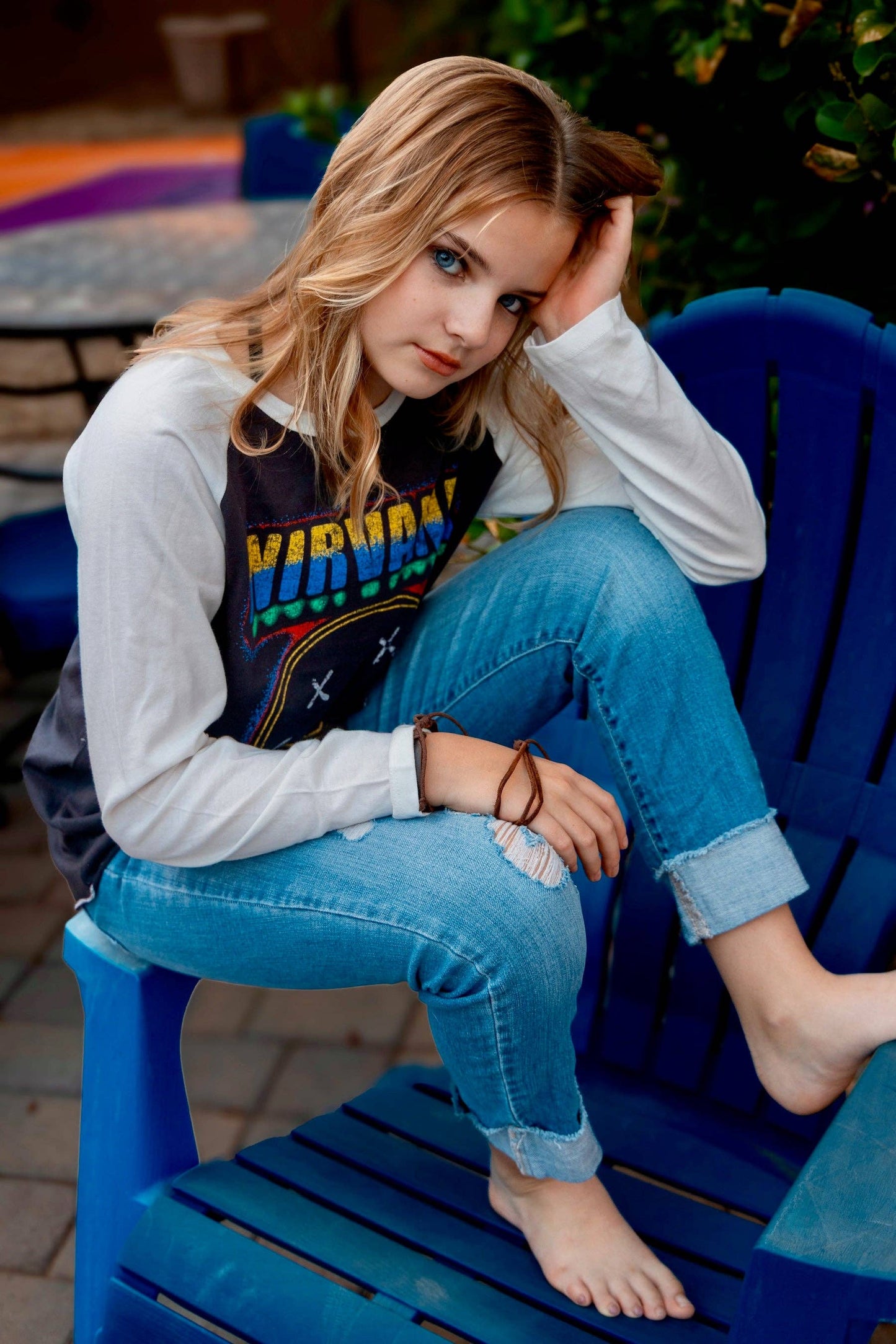 Person wearing a Nirvana shirt sitting on a blue chair outdoors.