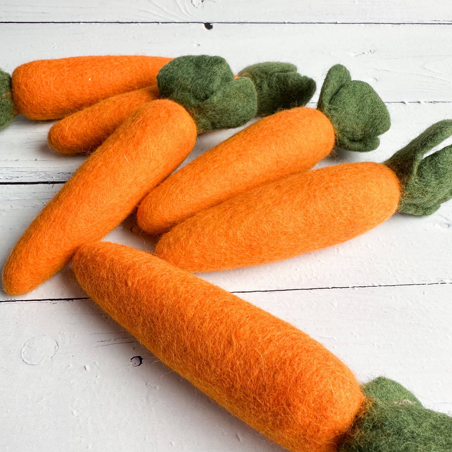 6 large felt carrots on a wooden table