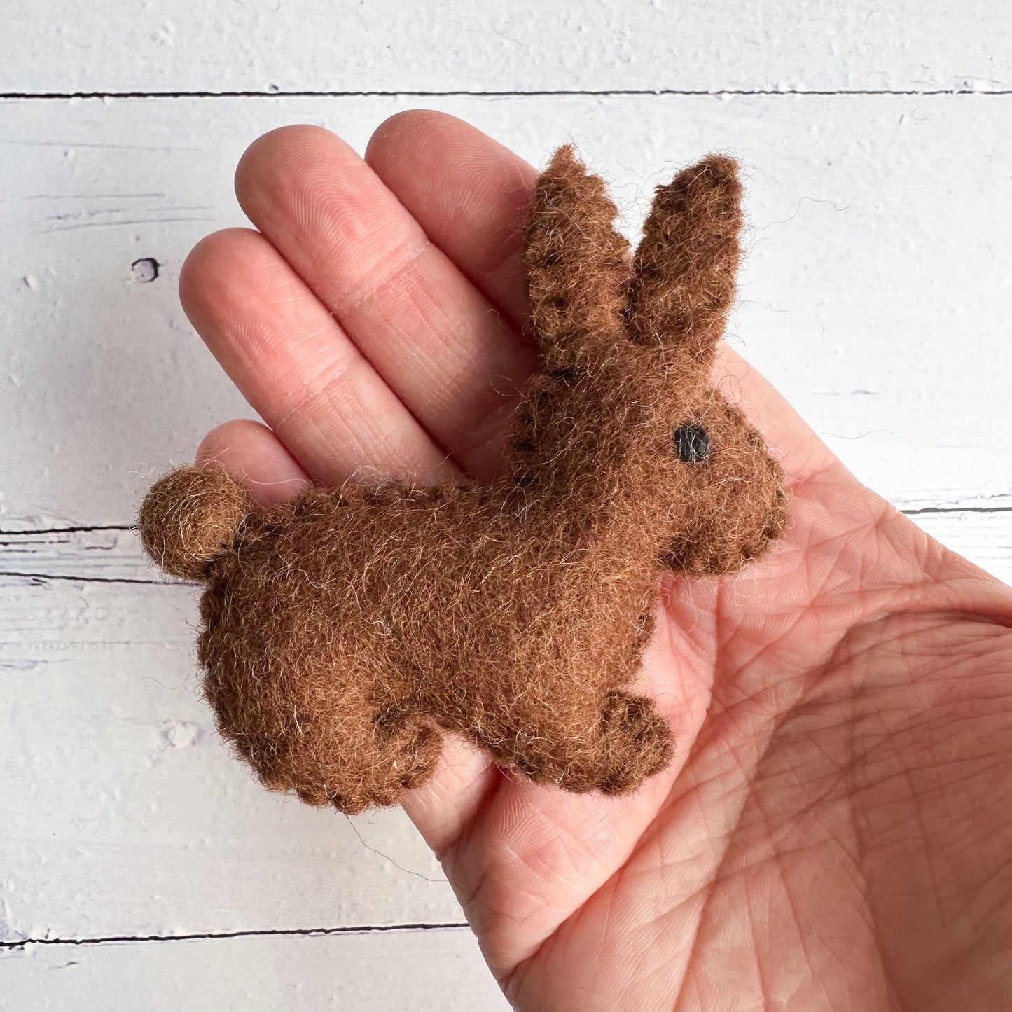 a hand holding a small felt chocolate bunny