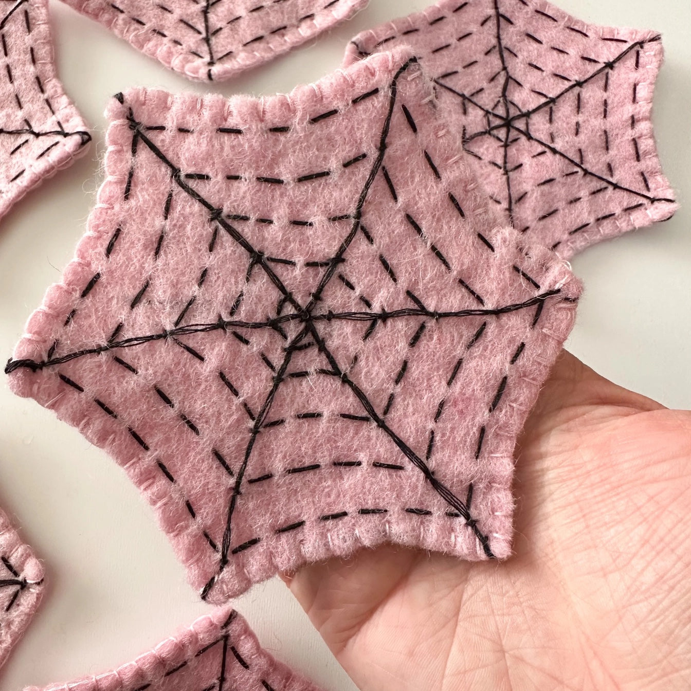 Hand holding a pink felt spider web