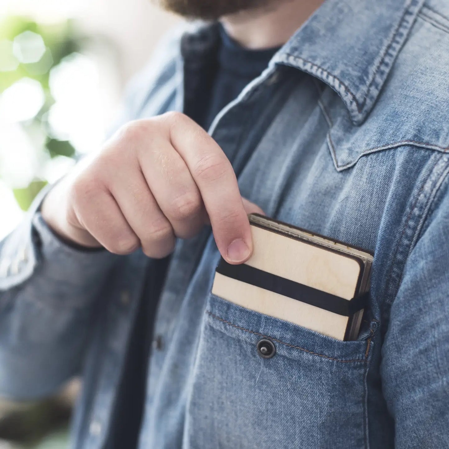 Person wearing a denim jacket with a flower press in the pocket