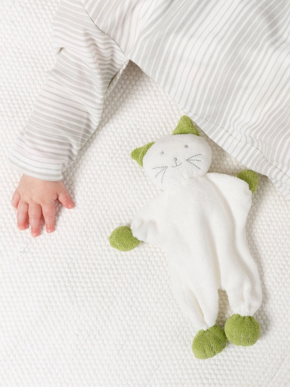 cece cat baby toy laying flat next to a baby's hand