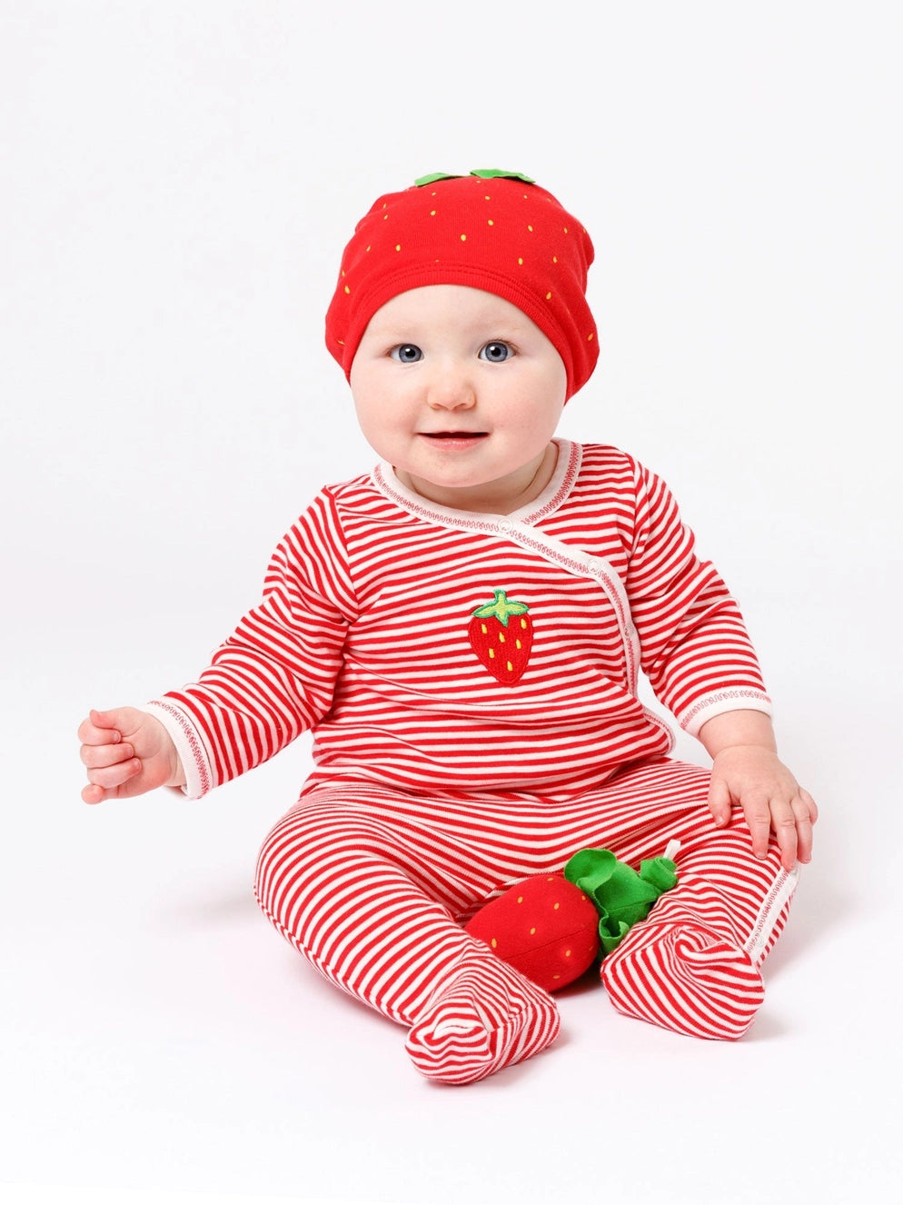 baby in a strawberry themed outfit holding a strawberry toy