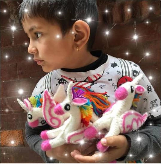 child holding three small felt rainbow unicorns
