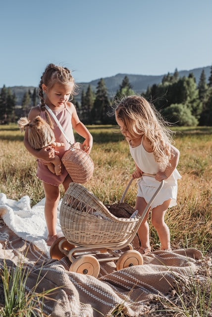 kids playing with dolls and a Poppie Rattan Doll Pram