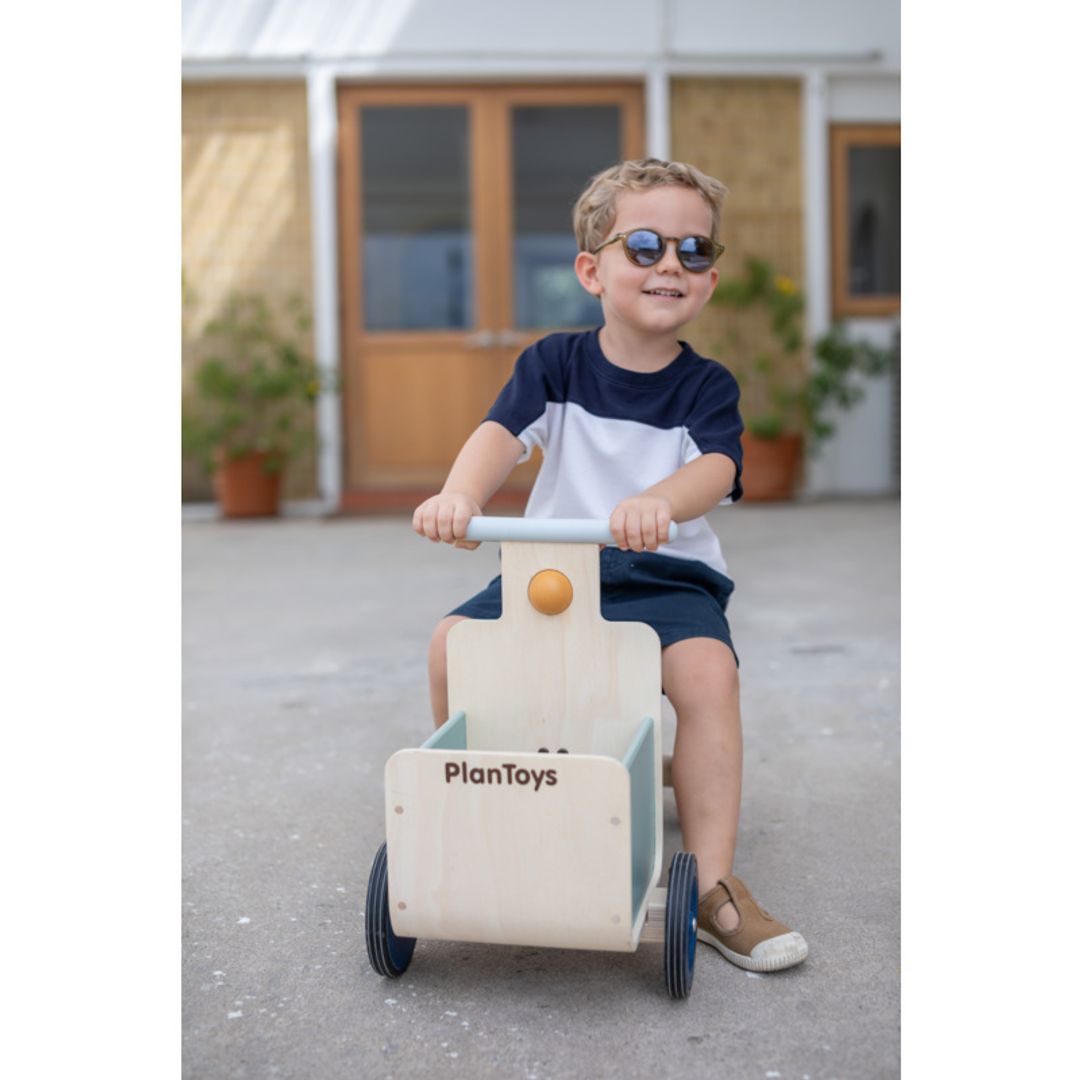 Child playing with a Delivery Bike in Orchard  by plan toys