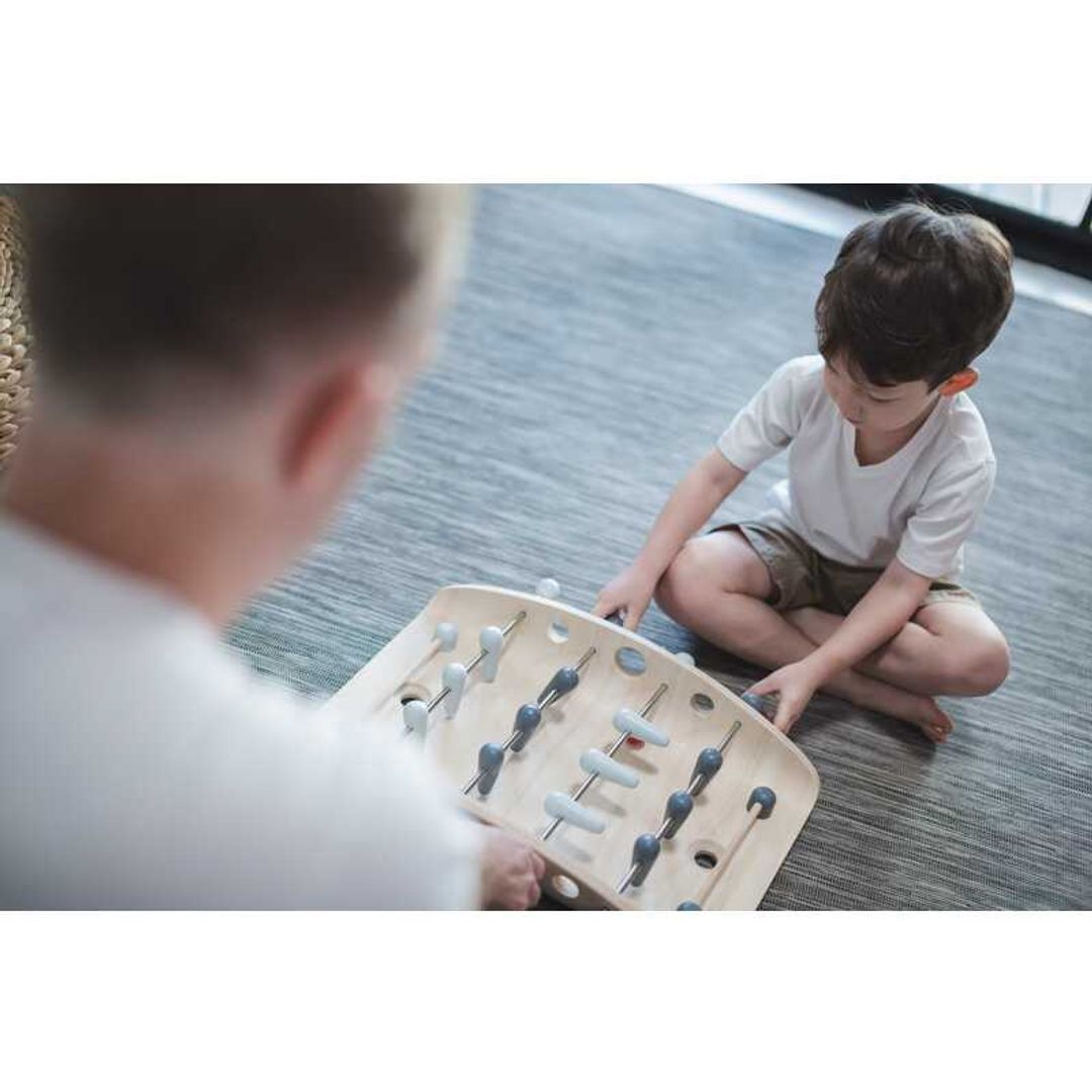 kid playing with a wood soccer game by Plan Toys