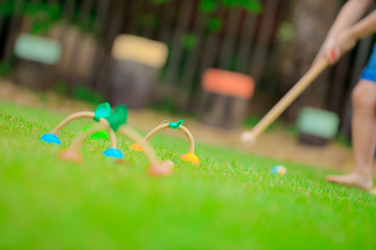 children playing outside with a Croquet Set by Plan Toys
