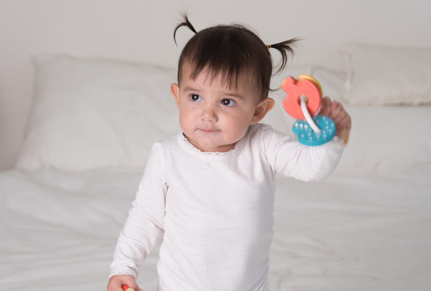 Child holding Key Rattle by Plan Toys