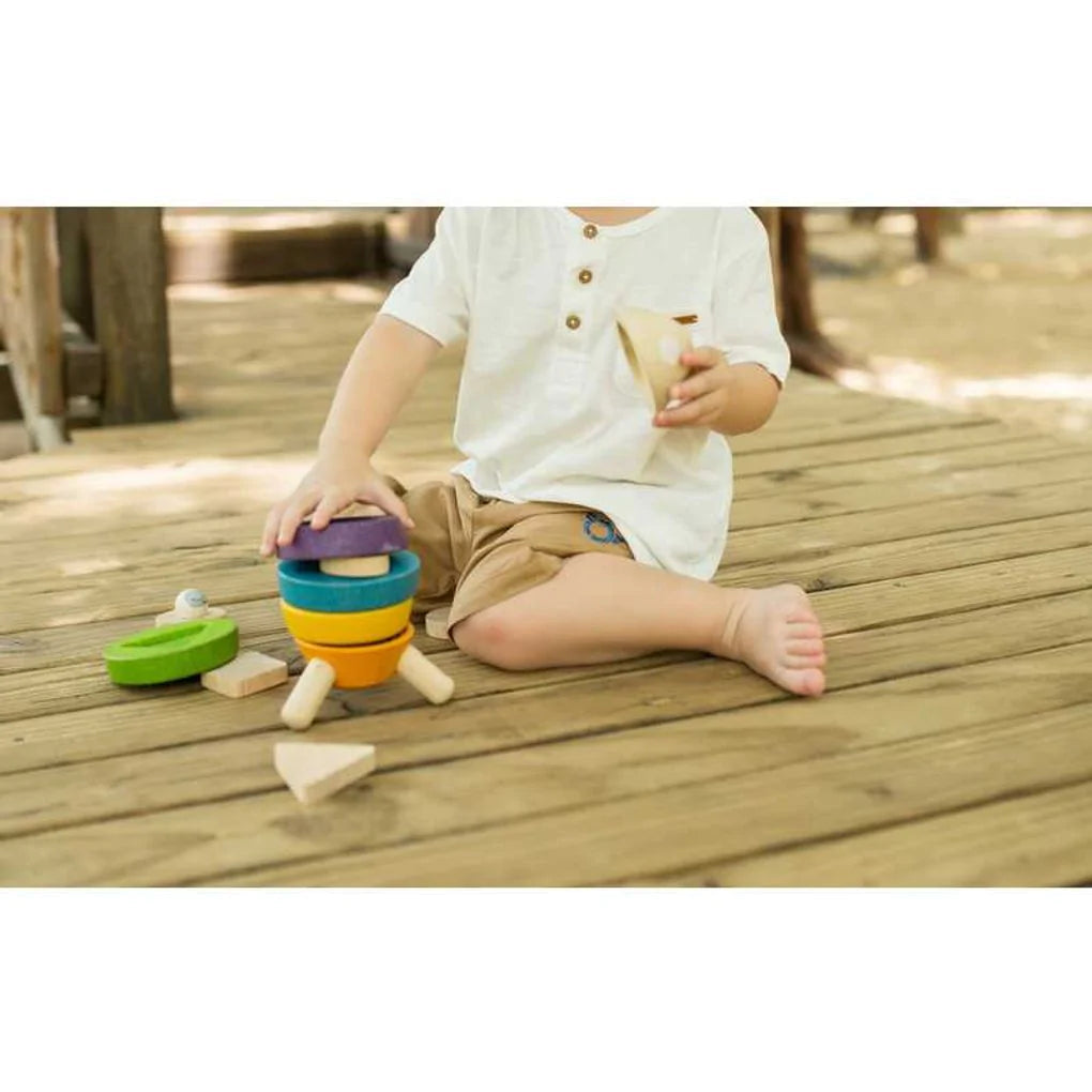 Child sitting on a wooden porch playing with stacking rocket