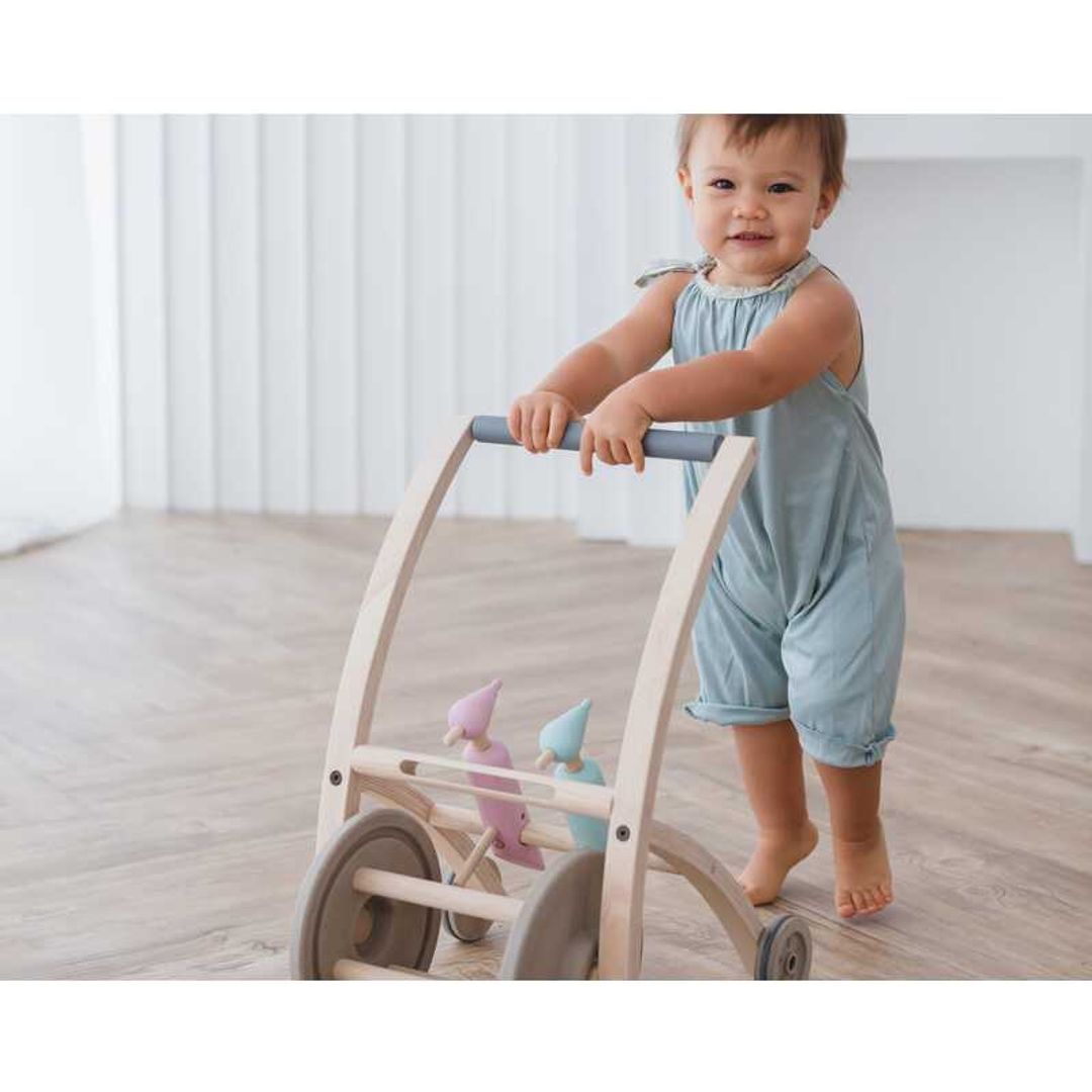 Toddler pushing a Woodpecker Walker BY PLAN TOYS