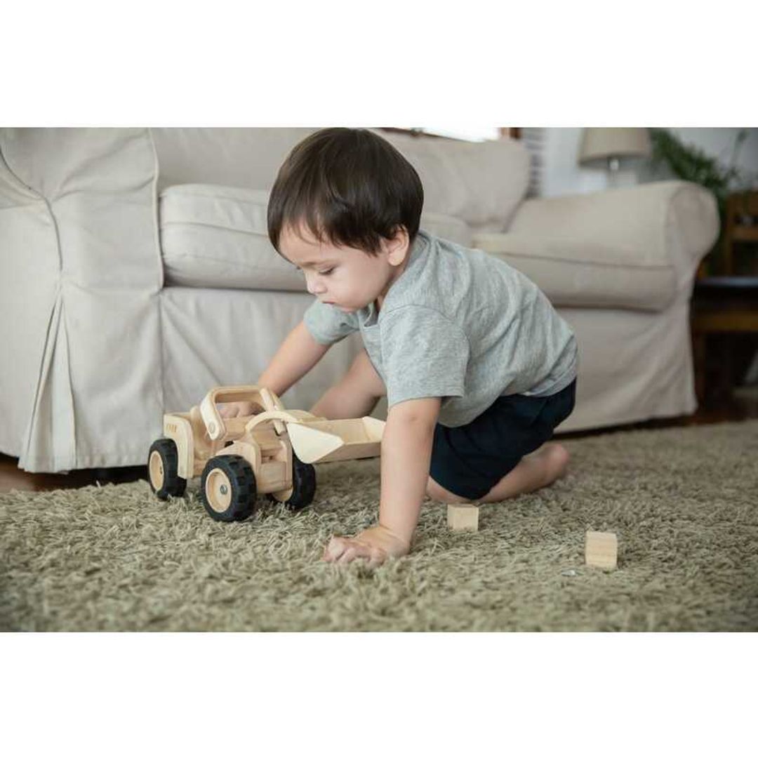 Toddler playing with a Bulldozer by Plan Toys