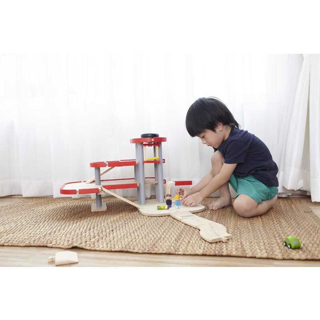 Child Playing with Parking Garage by Plan Toys