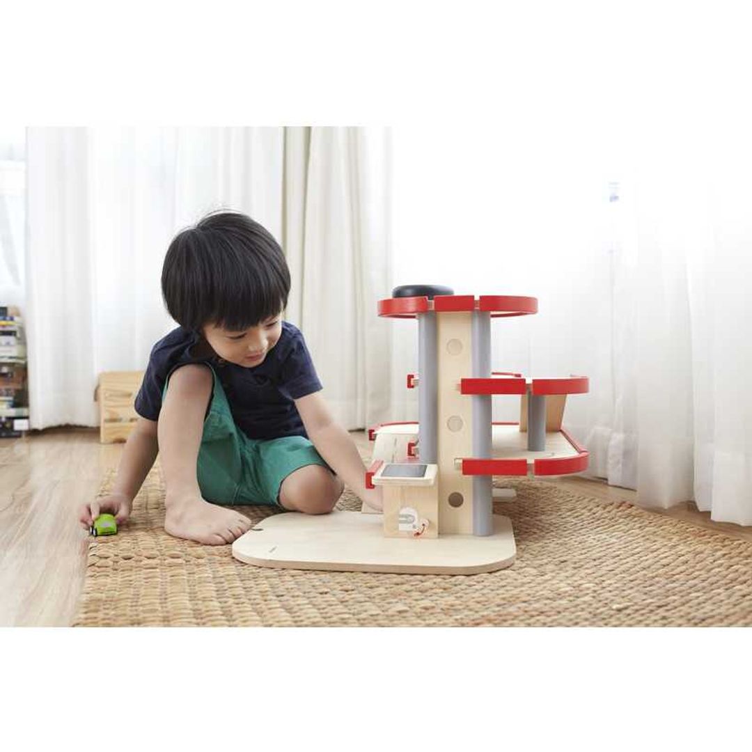 Child Playing with Parking Garage by Plan Toys