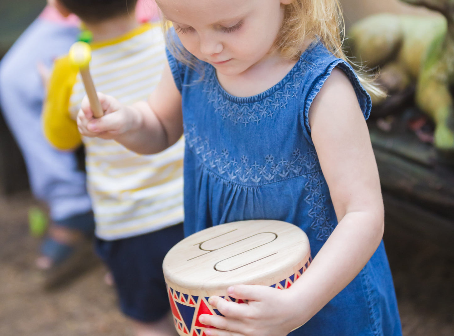 Child playing with Solid Drum by Plan Toys