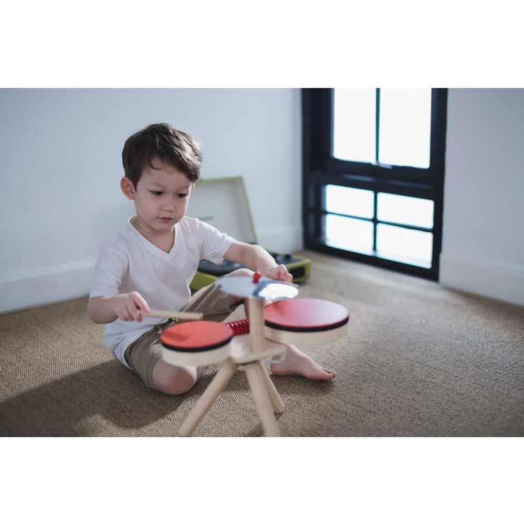 Kid playing the Musical Band Drum Kit by Plan Toys