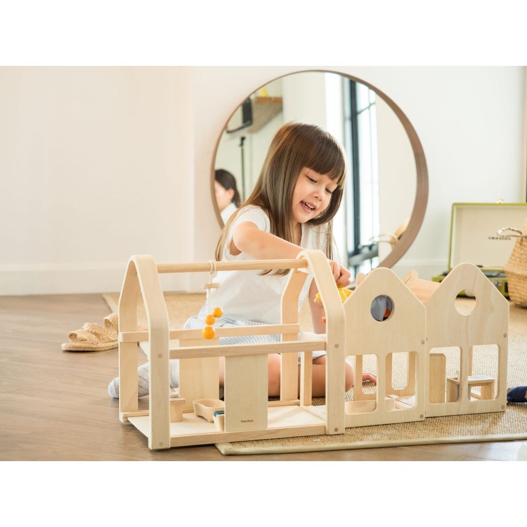 Child playing with Slide N Go Dollhouse by Plan Toys